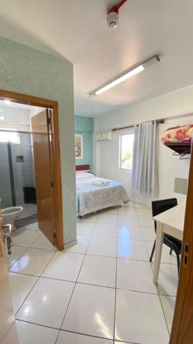 a bedroom with a bed and a room with a table at Hotel Zagonel in Chapecó