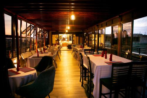 a restaurant with white tables and chairs and windows at Kaloni Hotels in Seeta