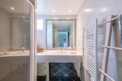 une salle de bain avec deux lavabos et un grand miroir dans l'établissement Modern Beachfront family apartment with pool, à Antibes