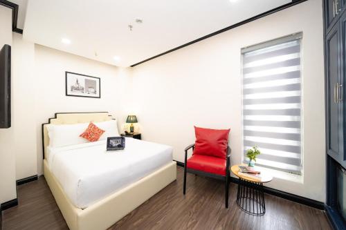 ホーチミン・シティにあるThe Passion Hotel Apartment - City Centralのベッドと赤い椅子のある寝室