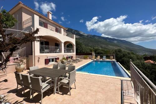 a villa with a swimming pool and a table and chairs at Villa Ionion Pelagos - infinity pool with magnificent sea views! in Vlachata