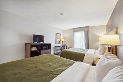 a hotel room with two beds and a flat screen tv at Quality Inn & Suites Dawsonville in Dawsonville