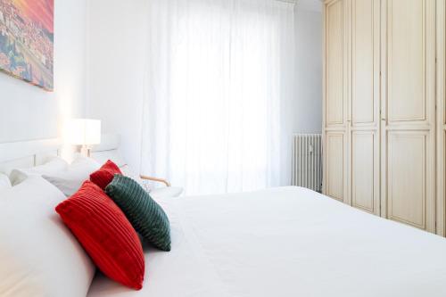 a white bedroom with red and green pillows on a bed at Godi Fiorenza Suite - Duomo a 15 Minuti e Aeroporto a 4 Minuti con Tramvia T2 in Florence