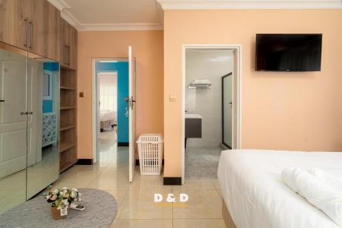 a bedroom with a bed and a tv on the wall at D & D Apartments in Lilongwe