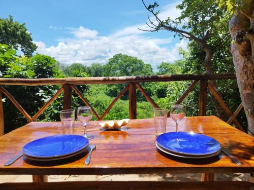 a wooden table with blue plates and glasses on it at MONKEY MOUNTAIN LODGE in Mtende