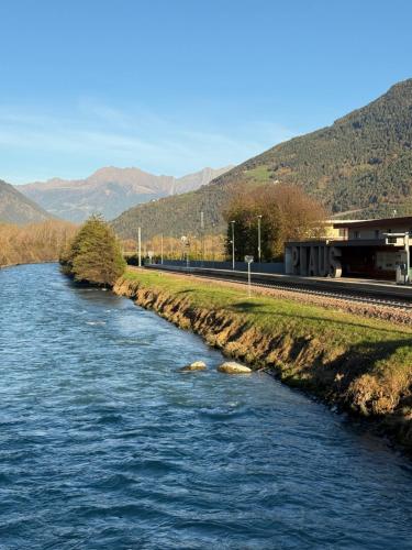 une rivière avec des rochers à côté d'une voie de train dans l'établissement Jacuzzi Suite Appartement bei Meran, à Merano