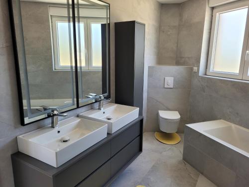 La salle de bains est pourvue de 2 lavabos, d'un miroir et de toilettes. dans l'établissement La maison des Daims, à Neufchef