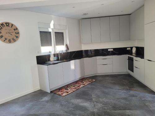 une cuisine avec des placards blancs et une horloge murale dans l'établissement La maison des Daims, à Neufchef