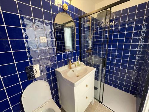 La salle de bains est pourvue de carrelage bleu, de toilettes et d'un lavabo. dans l'établissement Studio à deux pas des Calanques, à La Ciotat