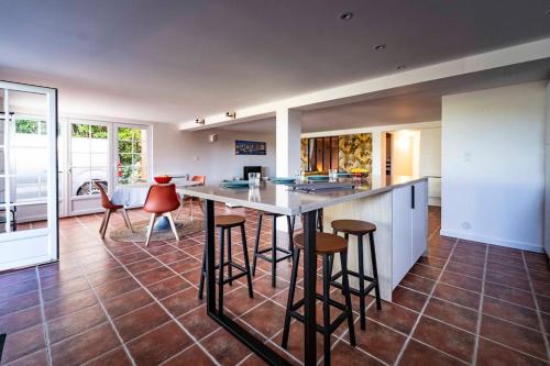 une cuisine avec une table et des tabourets dans une pièce dans l'établissement Bel appartement avec terrasse jardin vue montagne, à Souraïde