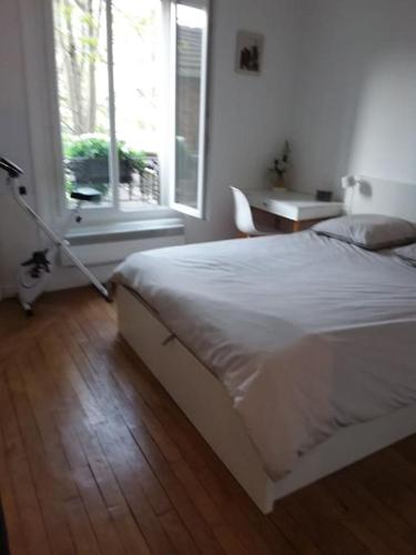 une chambre avec un lit blanc et une fenêtre dans l'établissement Appartement 40 m2 à, Boulogne Billancourt, à Boulogne-Billancourt
