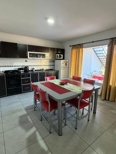 a kitchen with a table and red chairs in it at Complejo Turistico Los Troncos in San Rafael