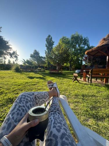 a person holding a cup of coffee in a park at Complejo Turistico Los Troncos in San Rafael