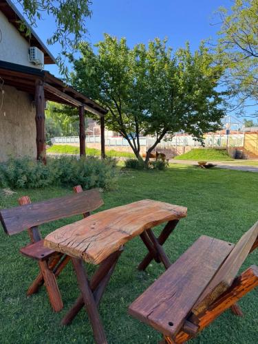 a wooden picnic table and bench in the grass at Complejo Turistico Los Troncos in San Rafael