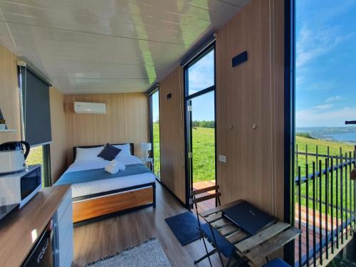 a bedroom with a bed and a balcony at Aorangi Peak Cabins 5 by Tiny Away in Rotorua