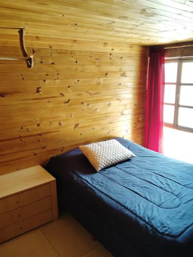 a bedroom with a blue bed in a wooden wall at Balcón serrano 2 in El Volcán