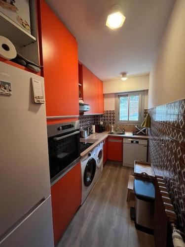 La cuisine est équipée d'armoires orange et d'un four avec plaques de cuisson. dans l'établissement Loft Edelweiss, à Font-Romeu-Odeillo-Via