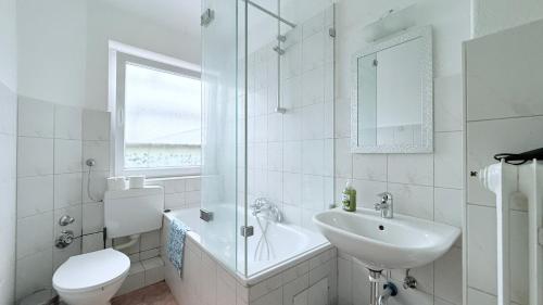 a white bathroom with a sink and a toilet at Neumünster Apartments direkt an der Stadthalle mit WLAN & Parkplatz in Neumünster