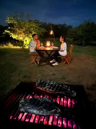 a man and woman sitting at a picnic table next to a grill at Ranakeliya Lodge - Yala in Yala