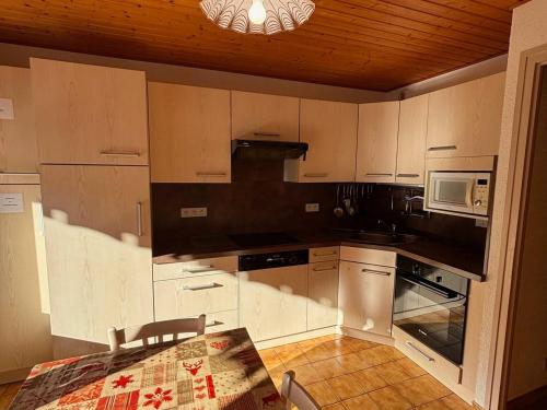 une cuisine avec des armoires blanches, une table et un micro-ondes dans l'établissement Chalet charmant avec balcon sud et Multi Pass à 3€/jour! - FR-1-692-22, à La Chapelle-dʼAbondance