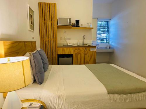 a bedroom with a large bed and a kitchen at Studios Downtown Cancun in Cancún