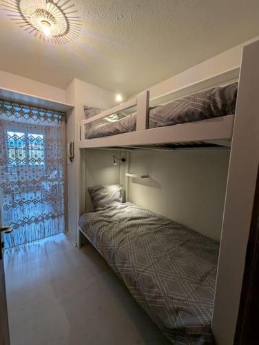 une chambre avec deux lits superposés et une fenêtre dans l'établissement Chez Paulette, Studio cosy au centre ville de Gérardmer, à Gérardmer