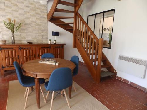 a dining room with a wooden table and blue chairs at Maison des oiseaux in Menou