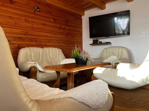 a living room with white furniture and a flat screen tv at Lesná Chata Barbara in Oravská Lesná