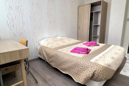 une chambre avec un lit avec des serviettes roses dessus dans l'établissement Appartement de 4 chambres, à Cholet