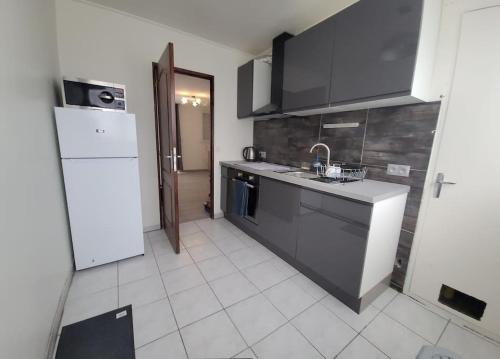 une cuisine avec un évier et un réfrigérateur blanc dans l'établissement Appartement de 4 chambres, à Cholet