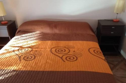 a bed with a brown bedspread with a design on it at Moana II in Las Grutas
