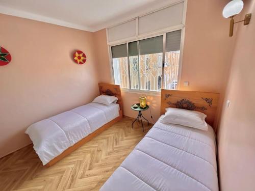 two beds in a room with a window at La perle de la Tour Hassan- Appartement Rabat in Rabat