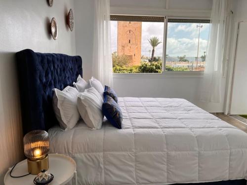 a bedroom with a large white bed with a window at La perle de la Tour Hassan- Appartement Rabat in Rabat
