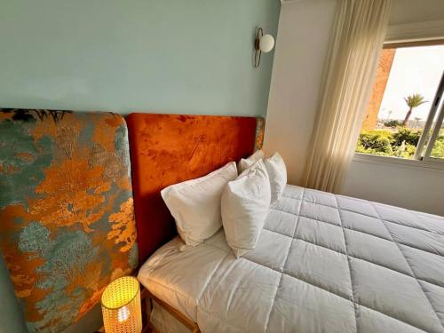 a bedroom with a bed with white pillows and a window at La perle de la Tour Hassan- Appartement Rabat in Rabat
