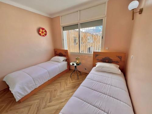 two beds in a room with a window at La perle de la Tour Hassan- Appartement Rabat in Rabat