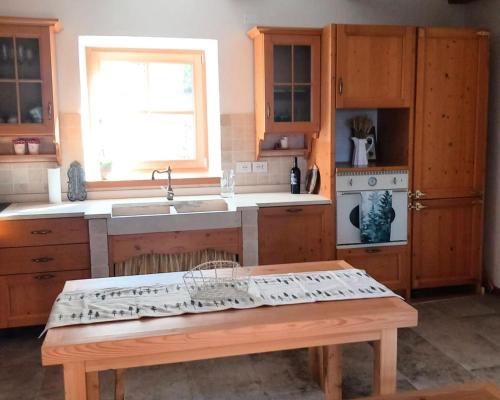 a kitchen with wooden cabinets and a sink and a bench at Mas dei Candidi in Baselga di Pinè