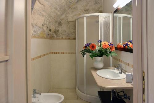 a bathroom with two sinks and a mirror and flowers at Relais Cimillà B&B in Ragusa
