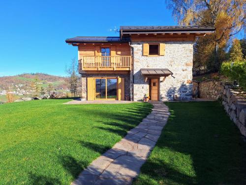 a house with a balcony on a green lawn at Mas dei Candidi in Baselga di Pinè