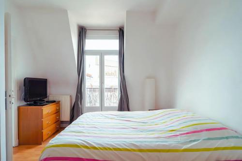 une chambre avec un lit, une télévision et une fenêtre dans l'établissement 2 pièces proche Palais des Congrès, à Paris