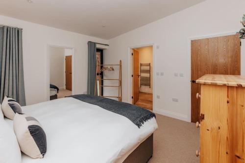 a bedroom with a white bed and a wooden cabinet at Cart Shed 2 in Nuneham Courtenay