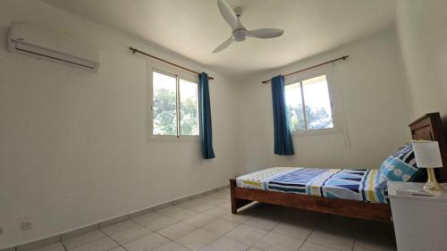 a bedroom with a bed and two windows at Maison Spacieuse et Confortable in Le Gosier