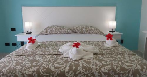 a bed with white towels and red flowers on it at All Seasons Hotel in Bayahibe