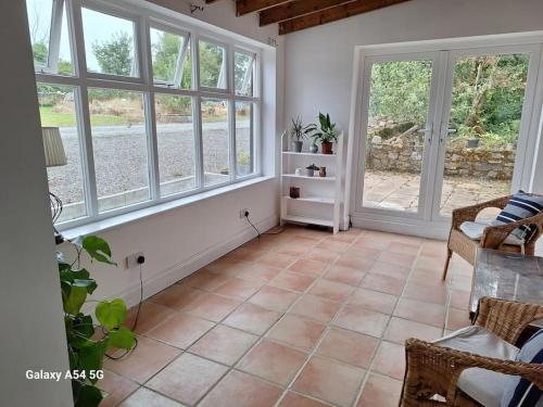 ein Wohnzimmer mit großen Fenstern und Fliesenboden in der Unterkunft The Stables in Aglish