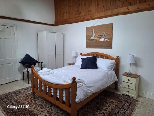 Schlafzimmer mit einem Holzbett mit weißer Bettwäsche und blauen Kissen in der Unterkunft The Stables in Aglish
