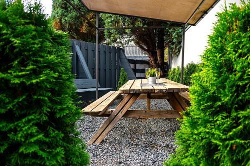 a wooden picnic table in a garden with two bushes at LiRo Hotel-Pension Haus Andrea in Niederkrüchten