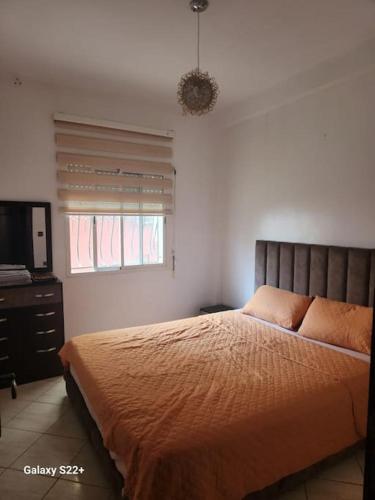 a bedroom with a bed and a flat screen tv at Naj'Appart TEMARA WIFAK CALME SITUÉ PRÉS DE LA GARE FERROVIAIRE 4 MIN A PIED in Temara