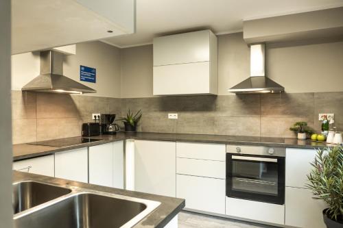 a kitchen with white cabinets and a sink at LiRo Hotel-Pension Haus Andrea in Niederkrüchten