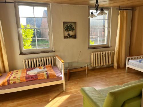 a bedroom with a bed and a table and two windows at Unterkunft Dähre in Dähre