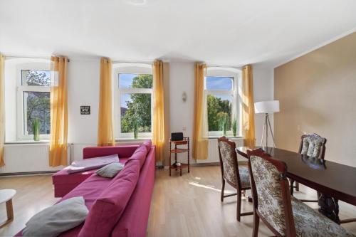 a living room with a couch and a table and windows at Schönes Ferien-Appartement für bis zu 6 Personen in Halberstadt