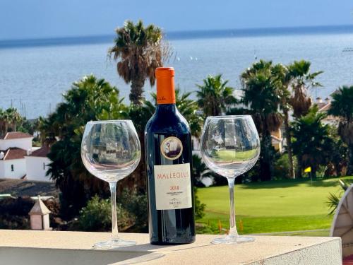a bottle of wine and two wine glasses on a table at Golf villa heated pool relax tenerife south in San Miguel de Abona